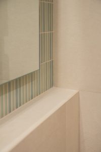 Detalle de la unión entre revestimiento cerámico verde en piezas pequeñas verticales y muro de recrecido con cerámica beige lisa de gran formato en el Proyecto Mallorca.